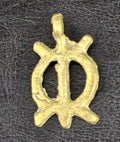 Small brass Wawa Aba pendant with an oval openwork center divided by a vertical bar, four projecting points, and a top hanging loop on dark fabric
