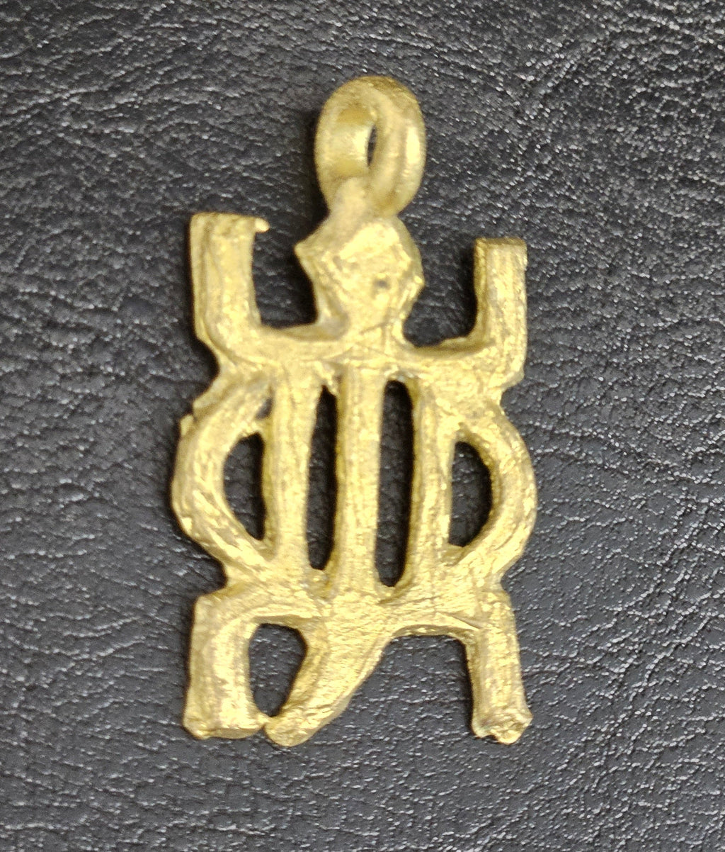 Brass openwork pendant with an oval center, projecting corners, and a top hanging loop on a dark textured background.