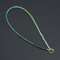 Ombré green cube bead necklace with gold-tone spacers and a toggle clasp on a dark background