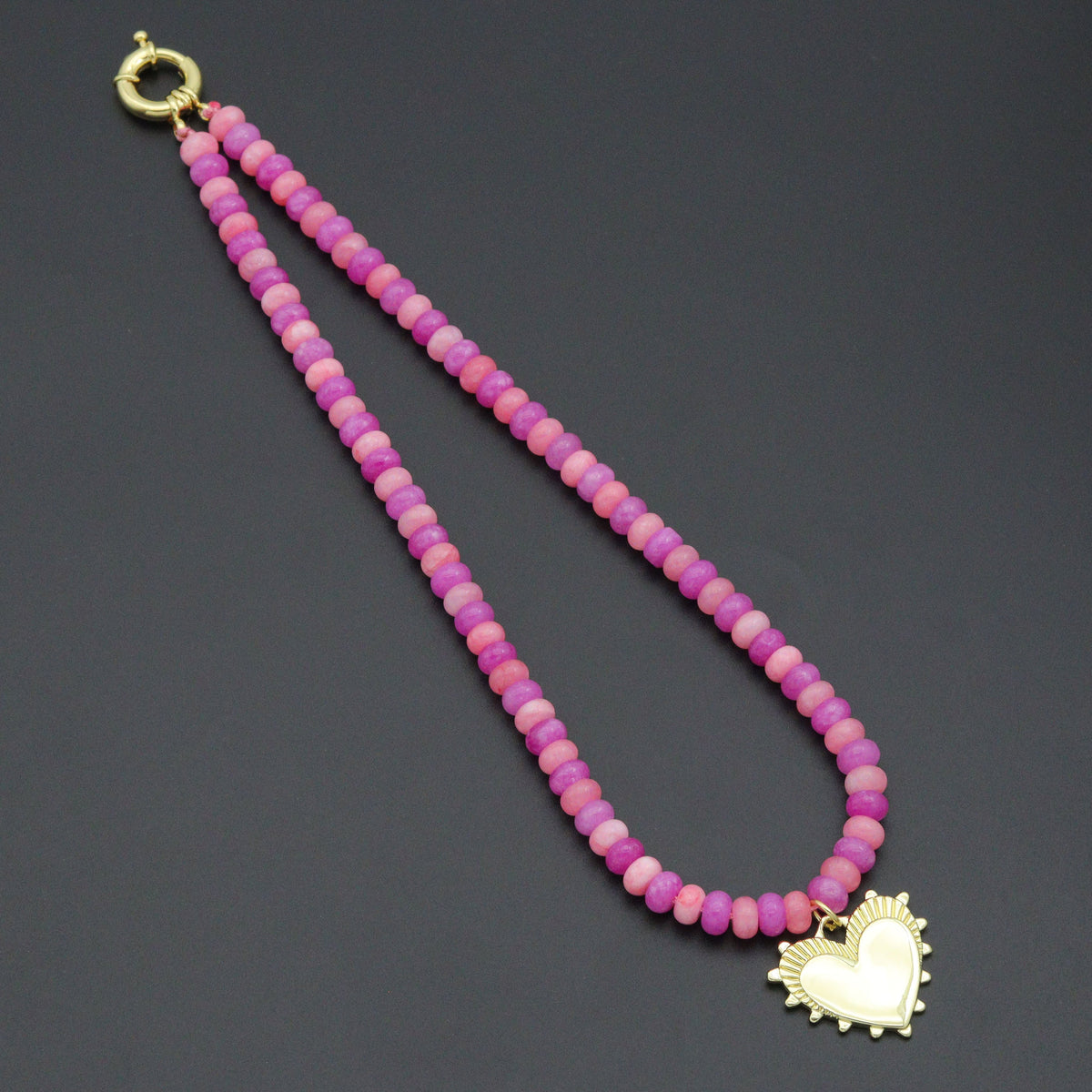 Pink and magenta rondelle bead necklace with a gold-tone heart pendant and round clasp