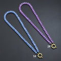 Blue and purple rondelle bead necklace with a gold-tone round clasp on a dark background
