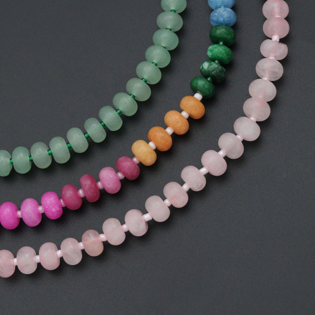 Close-up of pink and magenta rondelle beads with white spacers and a gold-tone round clasp