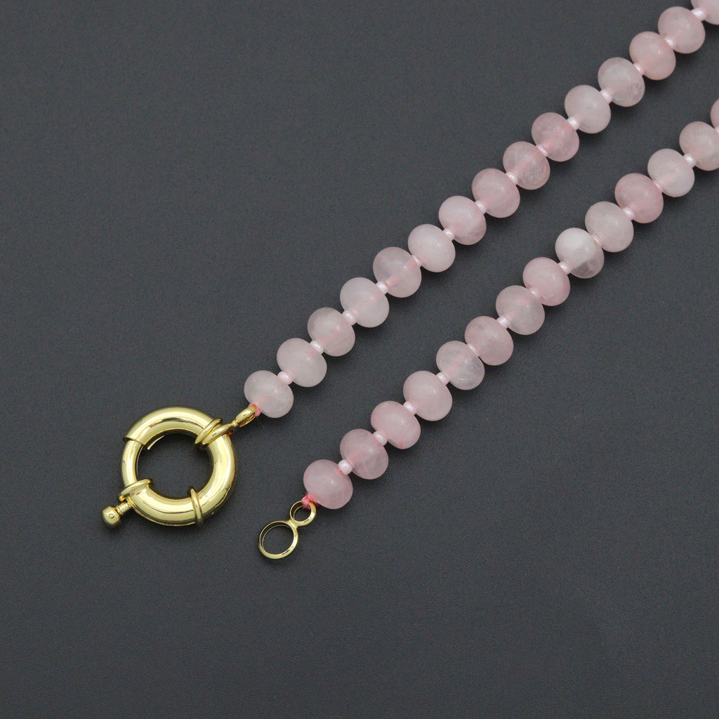 Close-up of green rondelle beads, white spacers and a gold-tone round clasp