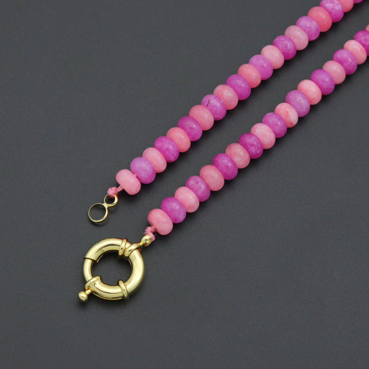 Pink bead necklace showing its unfastened gold-tone round clasp
