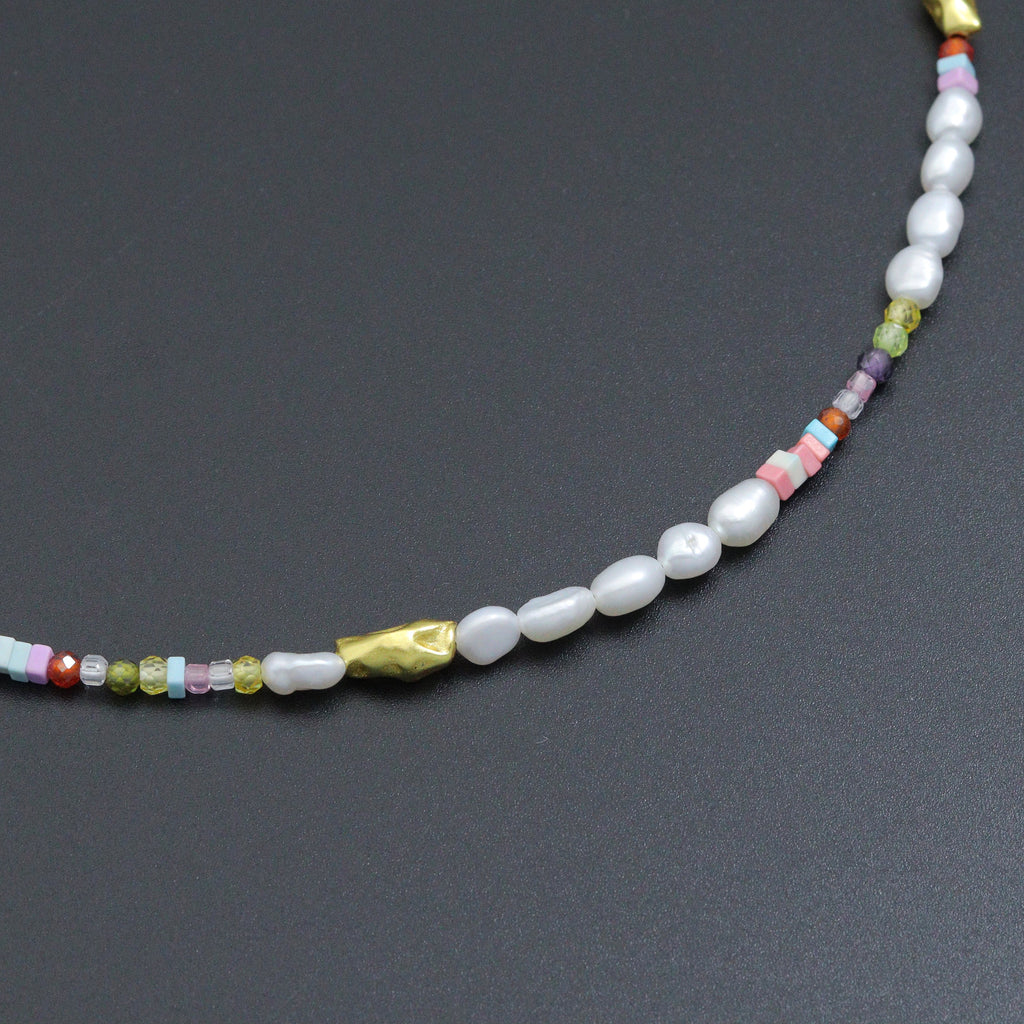 Close-up of white pearl beads, pastel cube beads and gold-tone accents