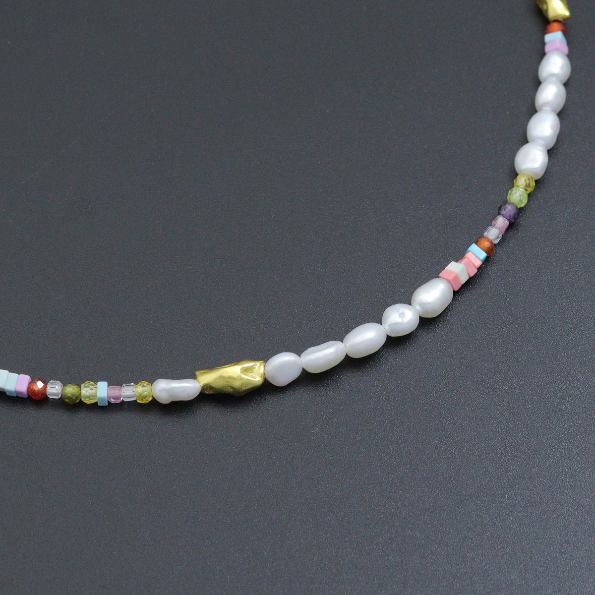 Close-up of white pearl beads, pastel cube beads and gold-tone accents