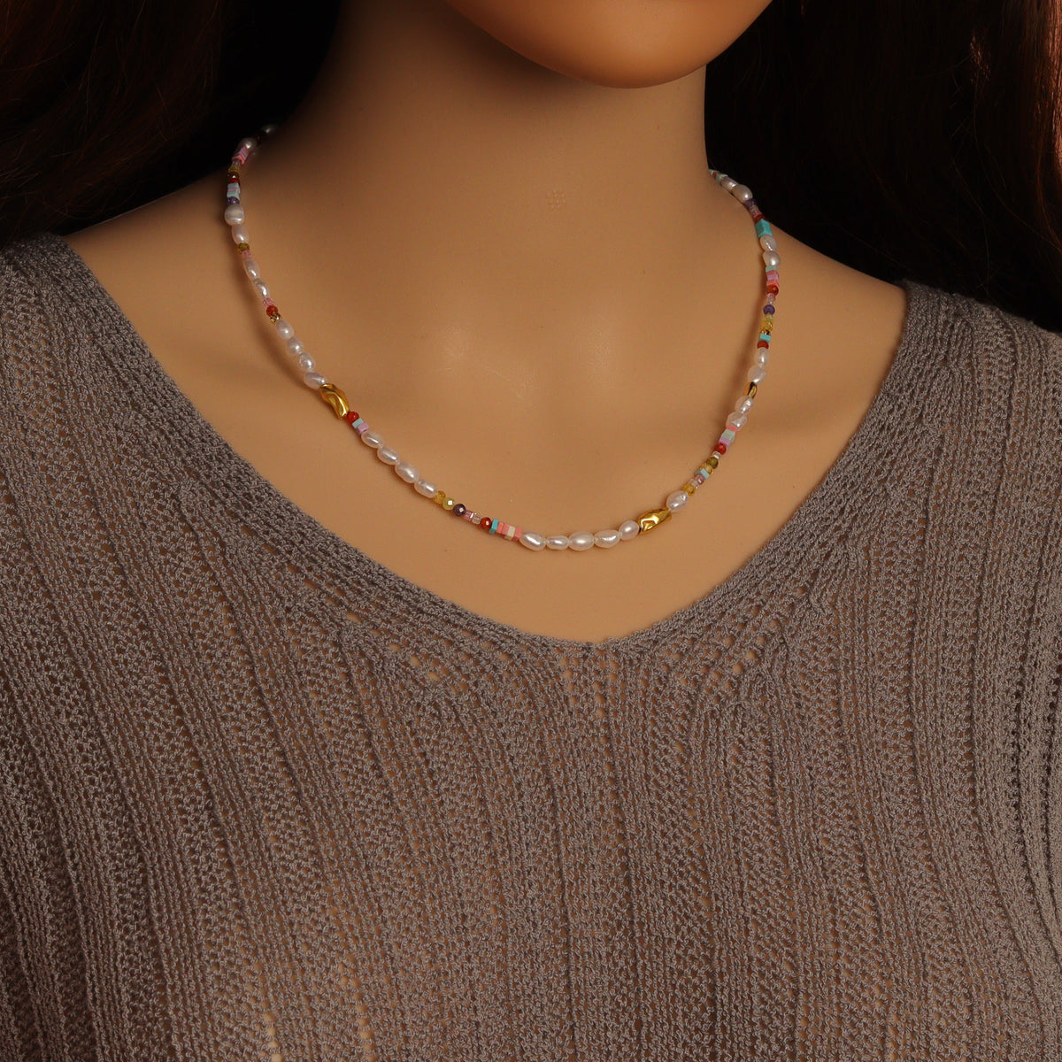 White pearl and multicolored bead necklace worn around the neck