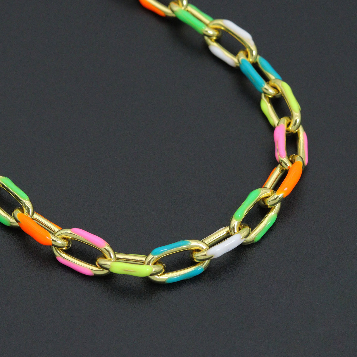 Close-up of gold-tone rectangular links with pink, orange, green and turquoise enamel accents