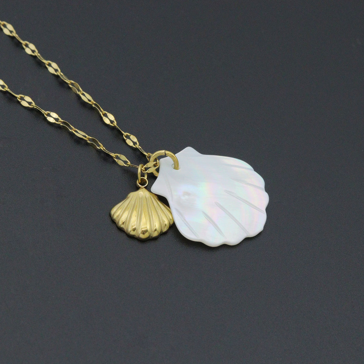Close-up of the white iridescent shell pendant and smaller gold-tone shell charm