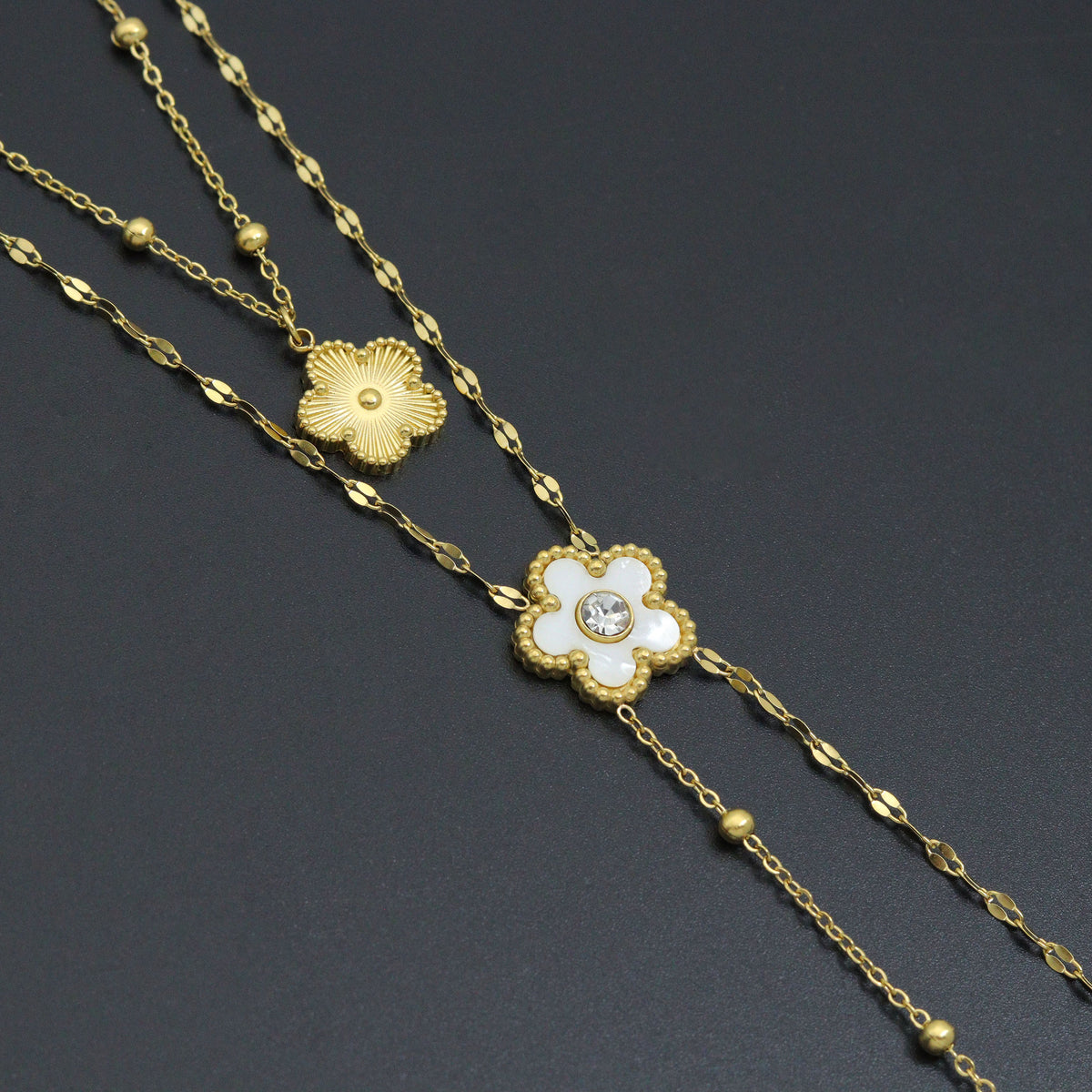 Close-up of a white flower with a clear center and a textured gold-tone flower charm