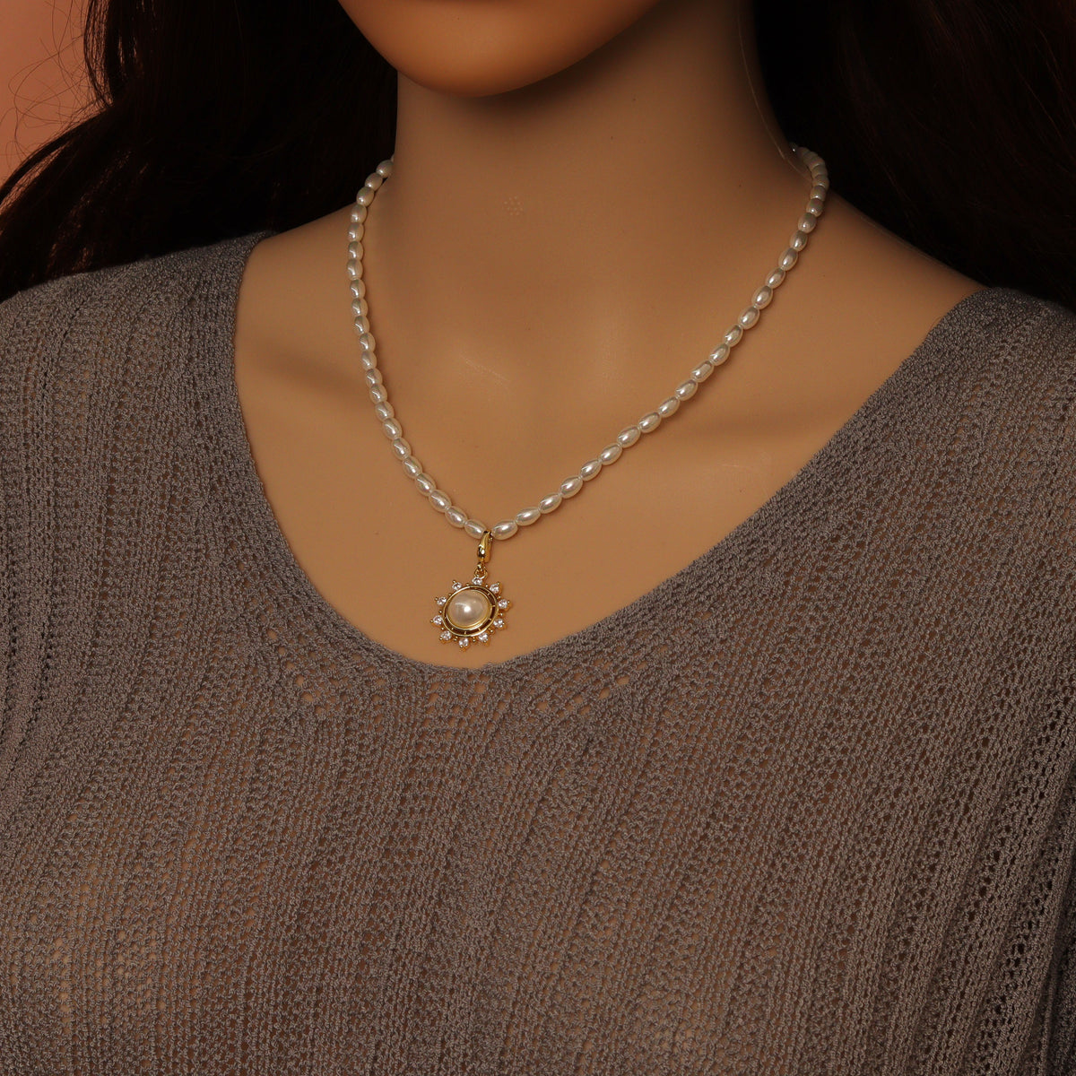 White rice-shaped bead necklace worn with a round pearl-centered pendant