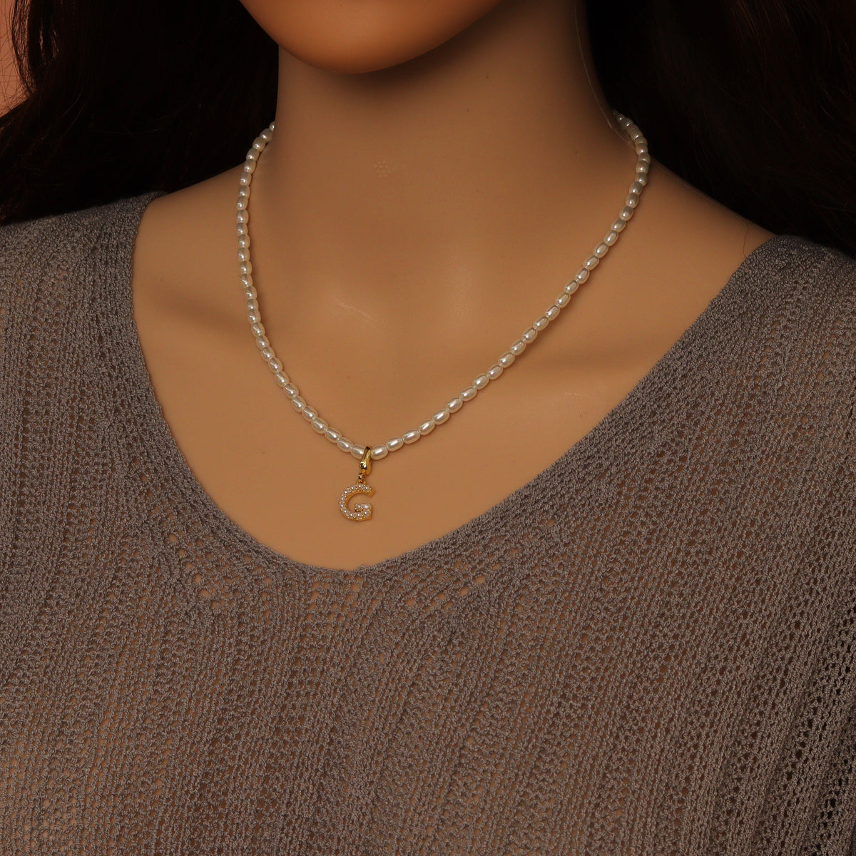 White rice-shaped bead necklace worn with a gold-tone letter C charm