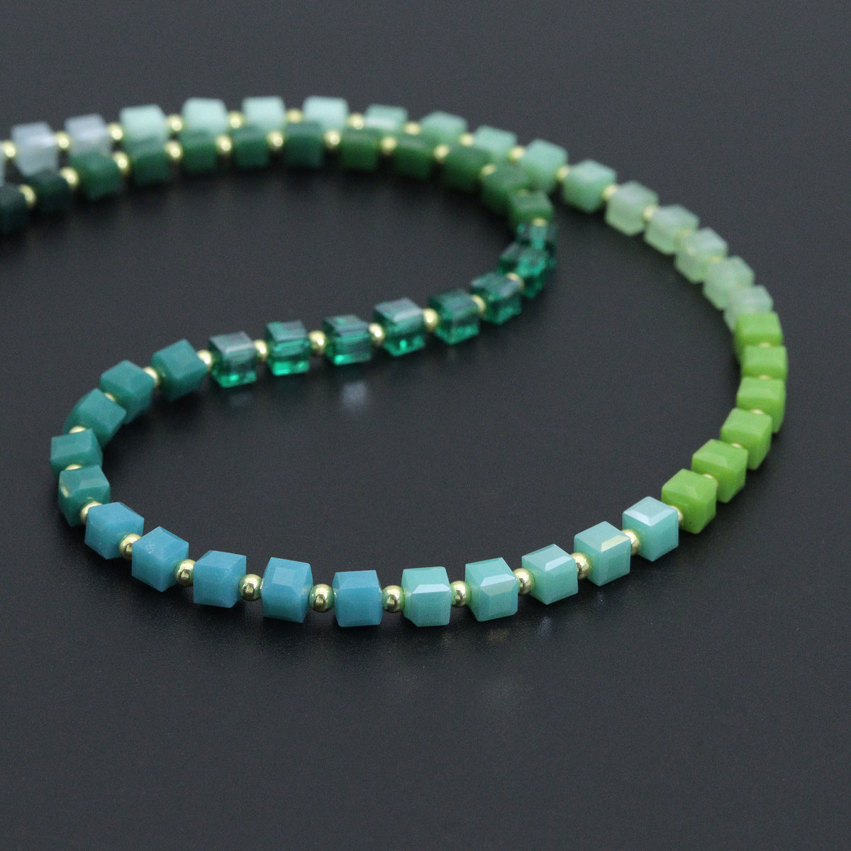 Close-up of teal, pale green and lime cube beads separated by gold-tone spacers