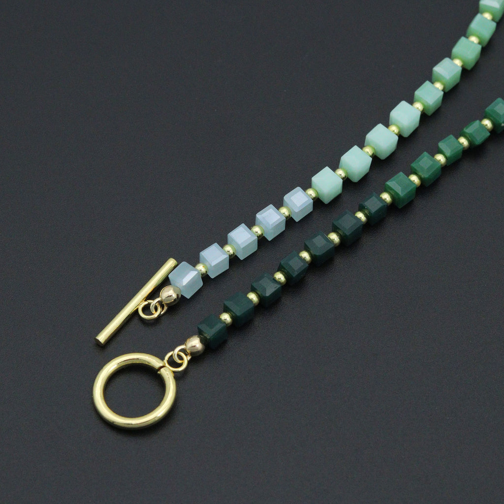 Close-up of the open gold-tone toggle clasp and pale and dark green cube beads