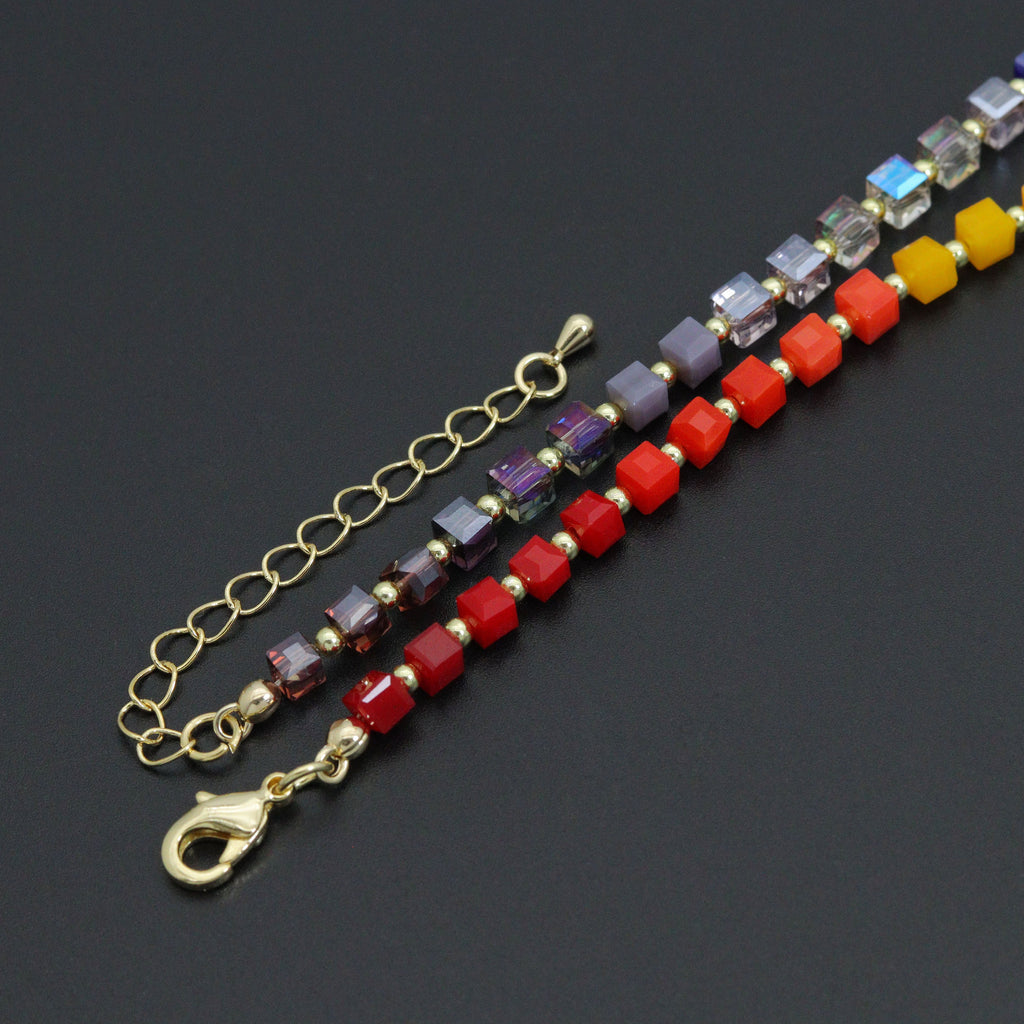 Rainbow cube necklace gold-tone lobster clasp and extender beside red and purple beads