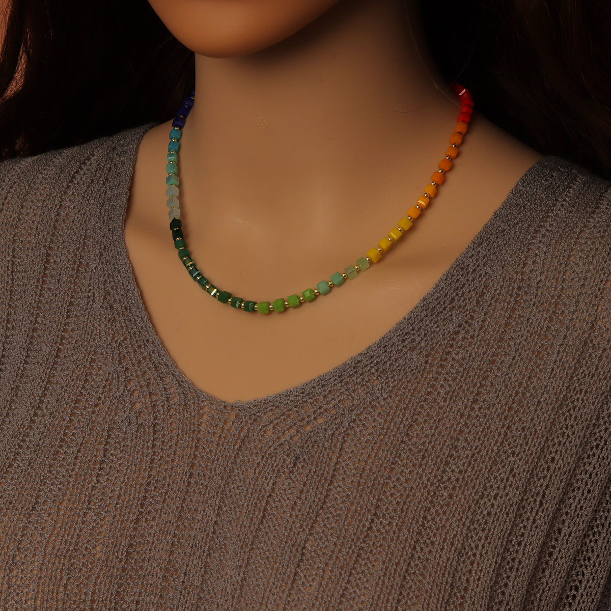 Rainbow cube bead necklace worn above a gray top