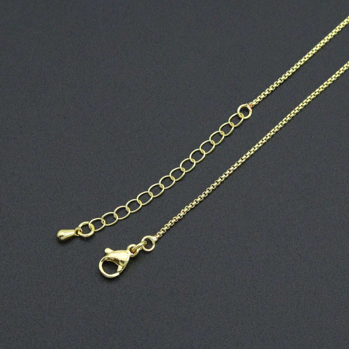 Close-up of the gold-tone box chain necklace lobster clasp and extender chain