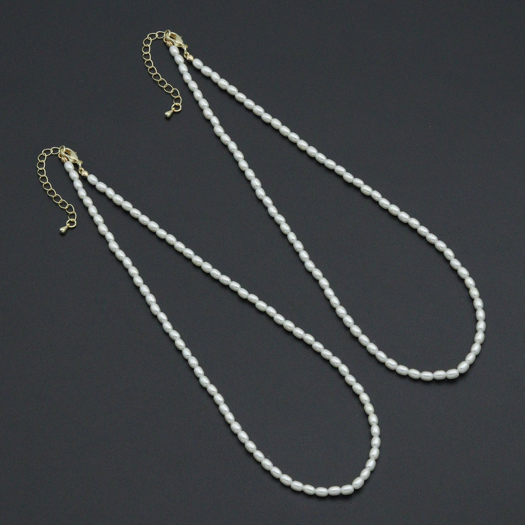 Two white rice-shaped bead necklaces with gold-tone lobster clasps and extender chains