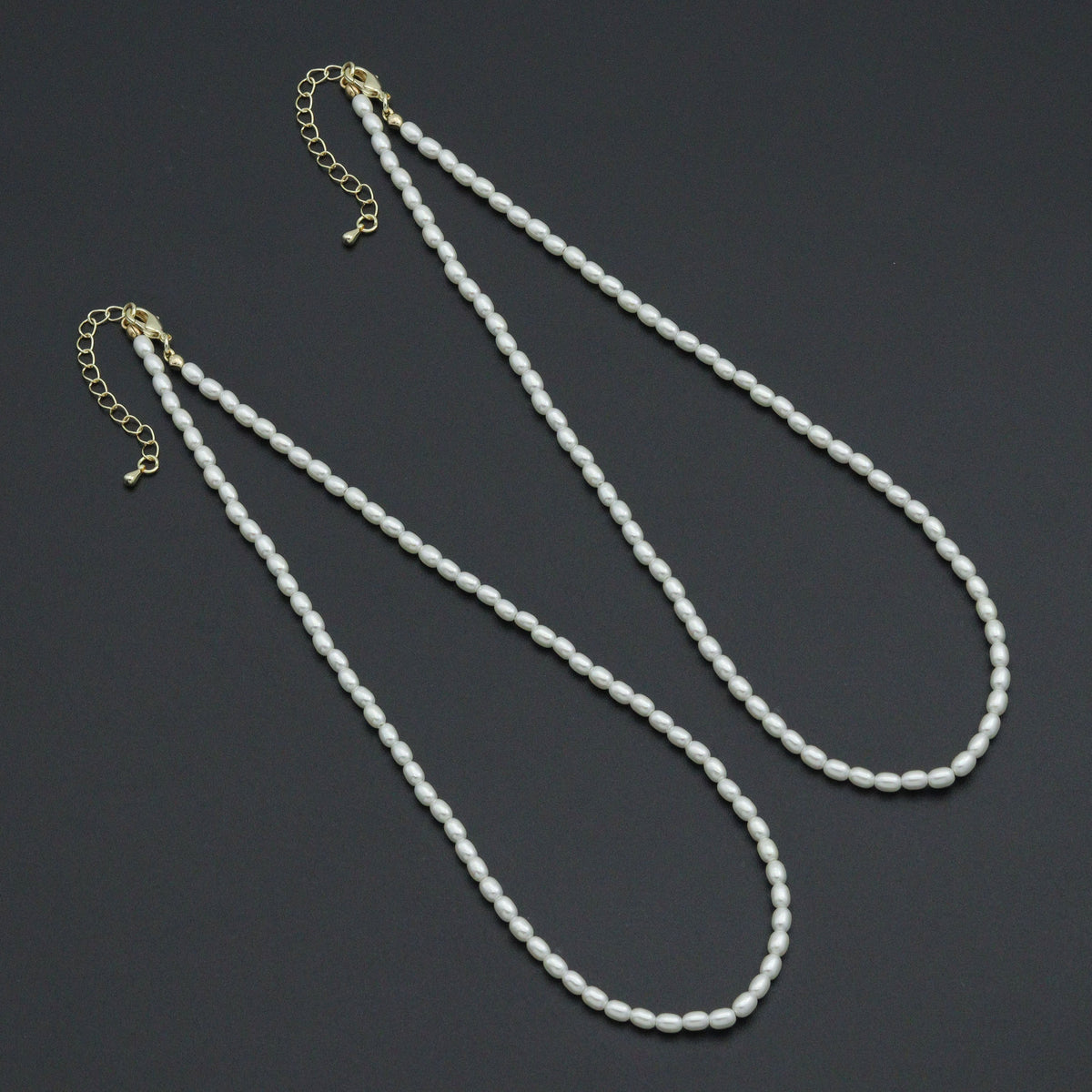Two white rice-shaped bead necklaces with gold-tone lobster clasps and extender chains