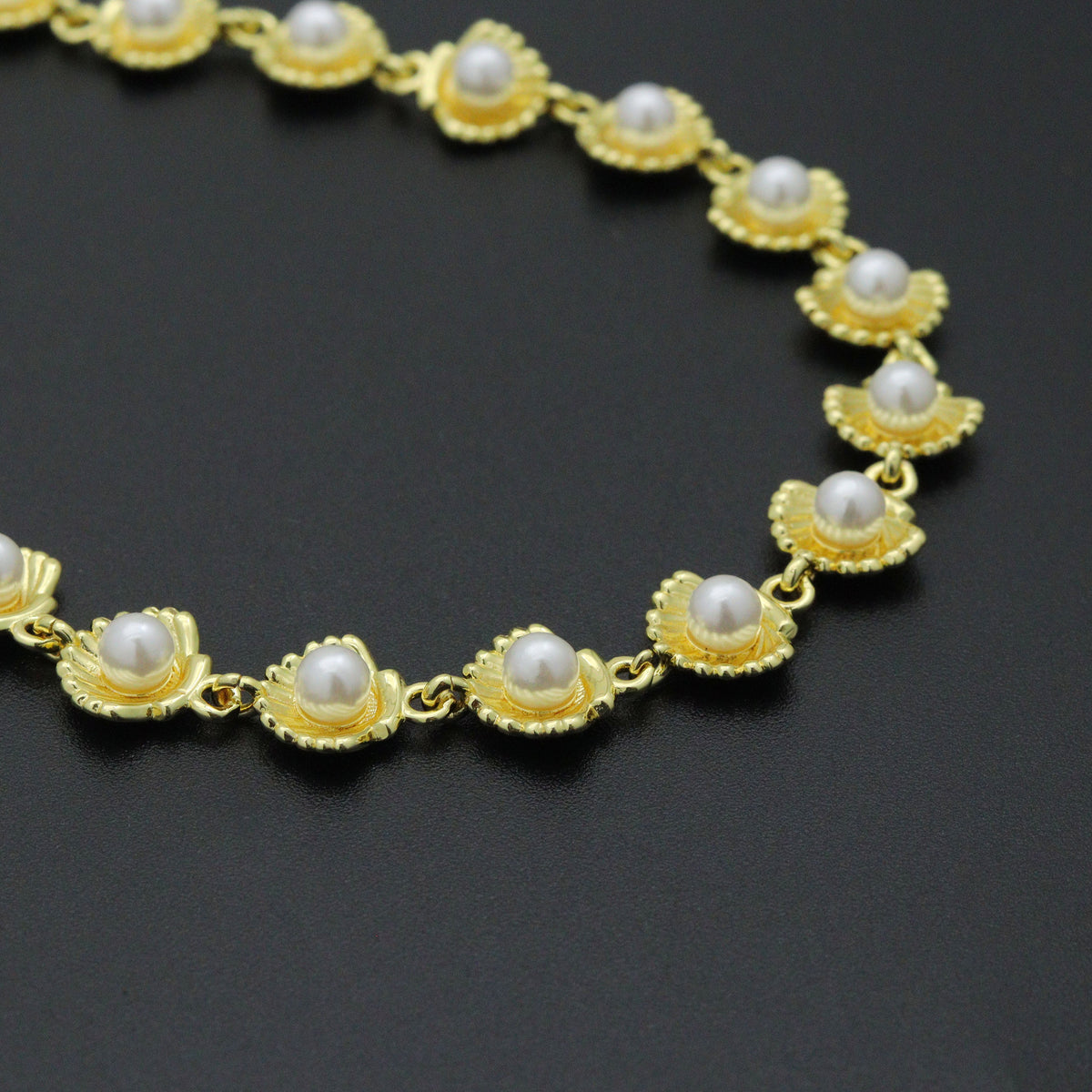 Close-up of white pearl-like beads in gold-tone shell-shaped settings