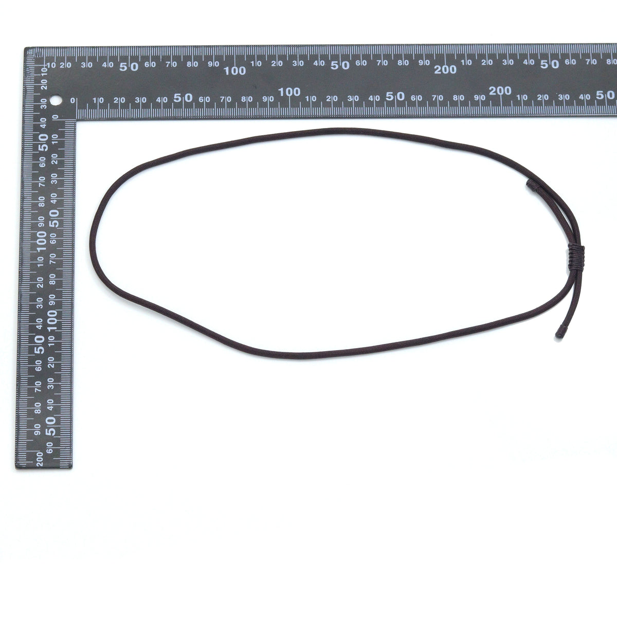 Adjustable cord necklace beside an L-shaped ruler for scale