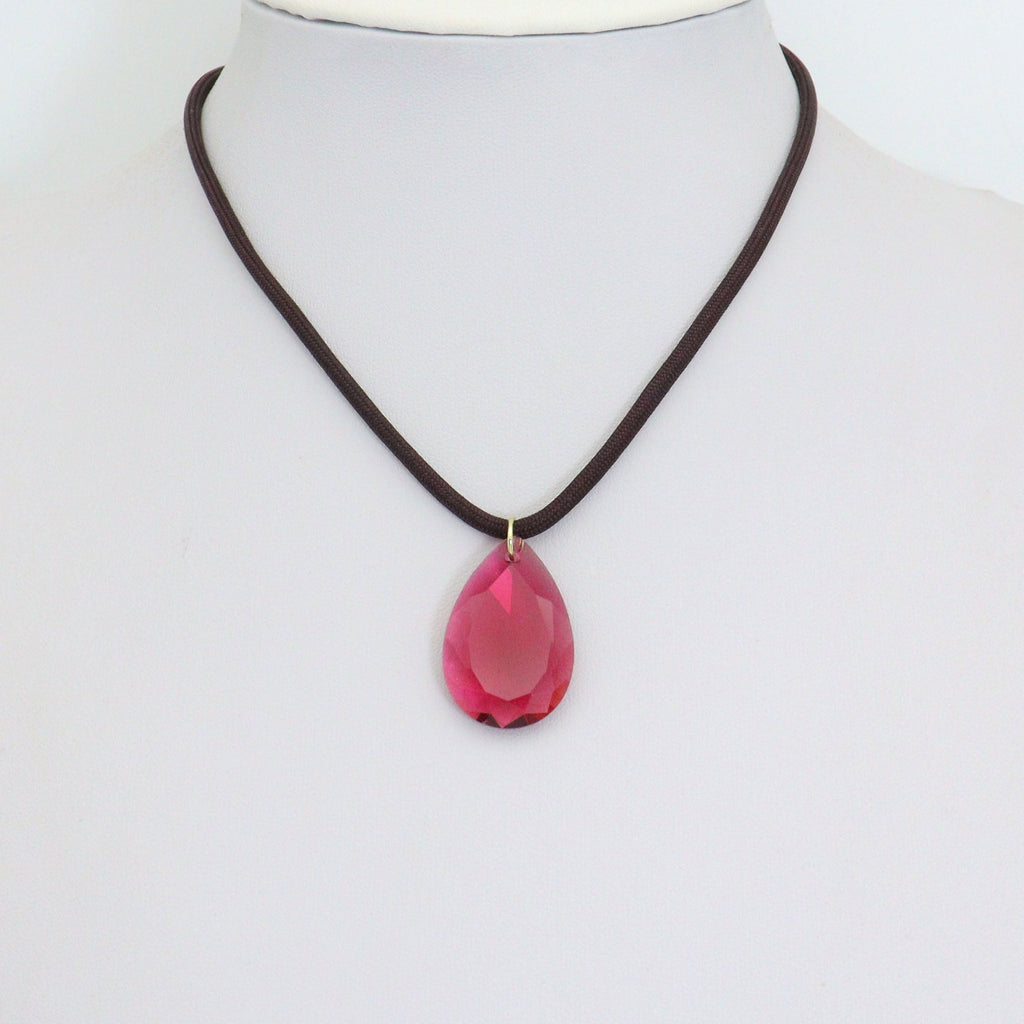 Dark cord necklace displaying a pink teardrop pendant on a white bust