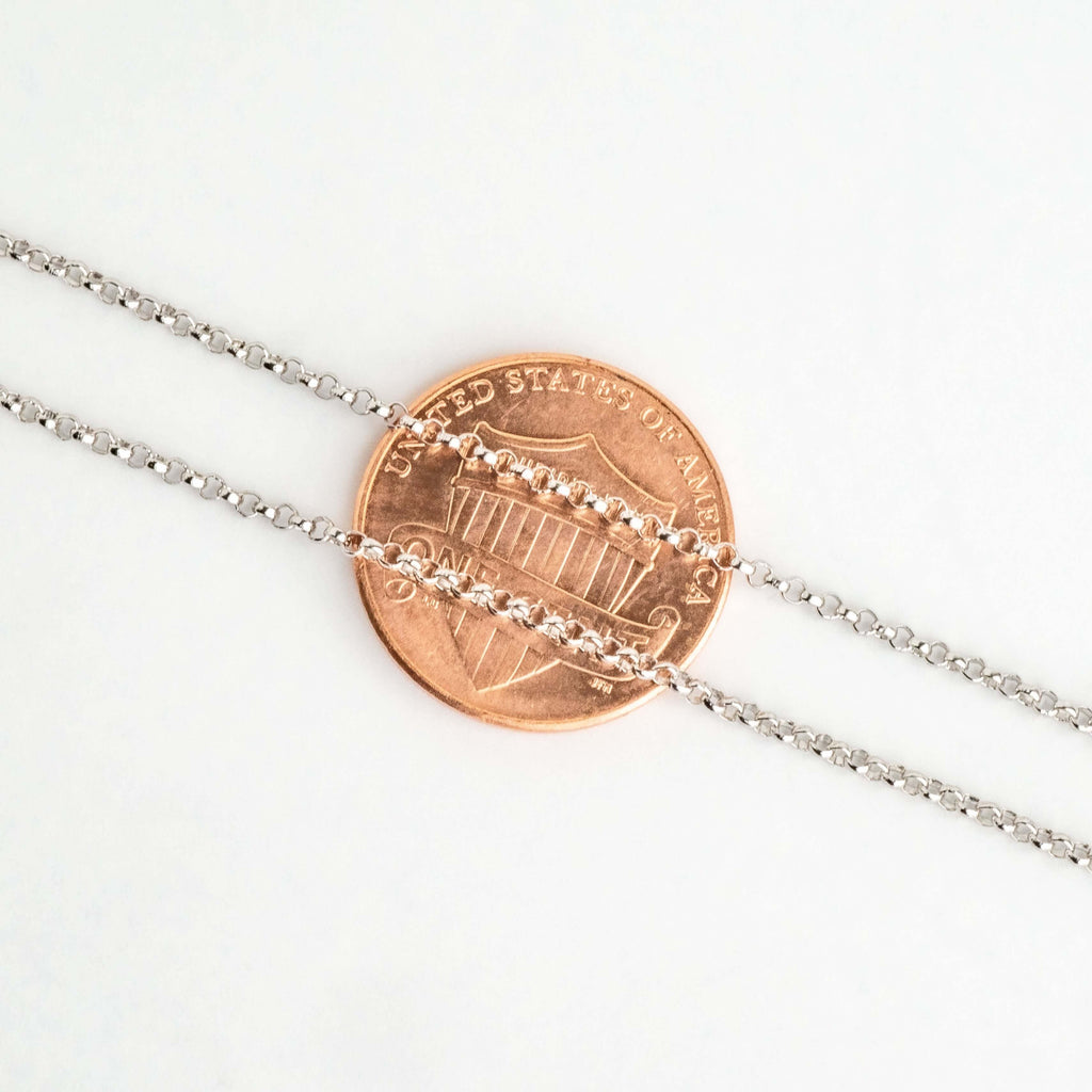 Close-up of sterling silver rolo chain links over a penny for scale