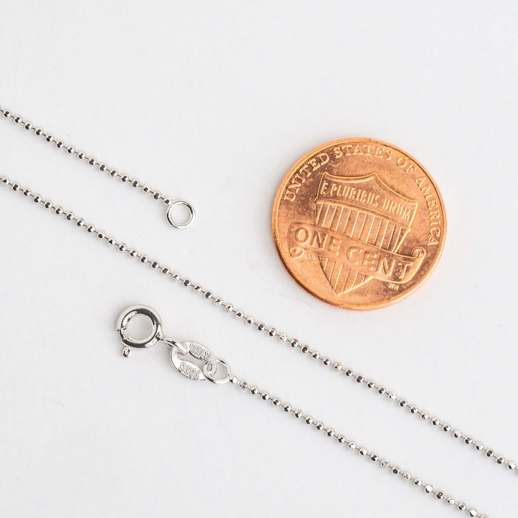 Ball chain necklace clasp and end ring beside a penny