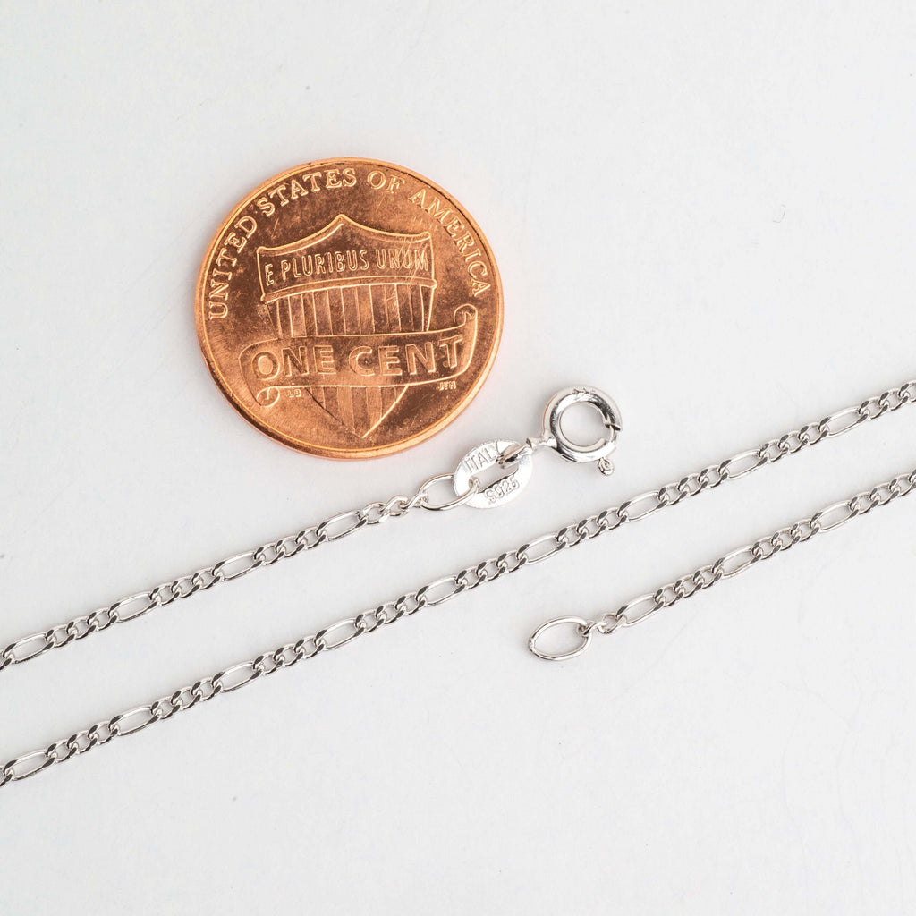 Figaro chain necklace clasp and links beside a penny for scale
