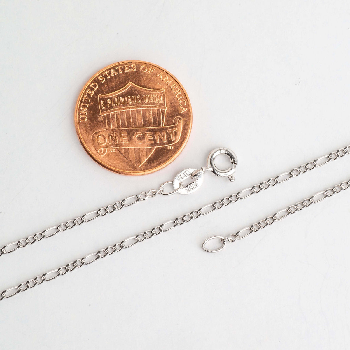 Figaro chain necklace clasp and links beside a penny for scale