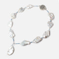 White irregular soufflé pearl necklace with pale blue spacer beads, a pearl drop and decorative silver-tone clasp