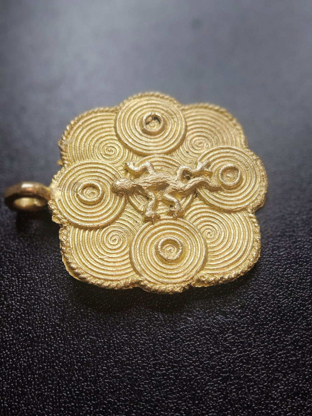 ashanti brass adinkra pendant dark background detail