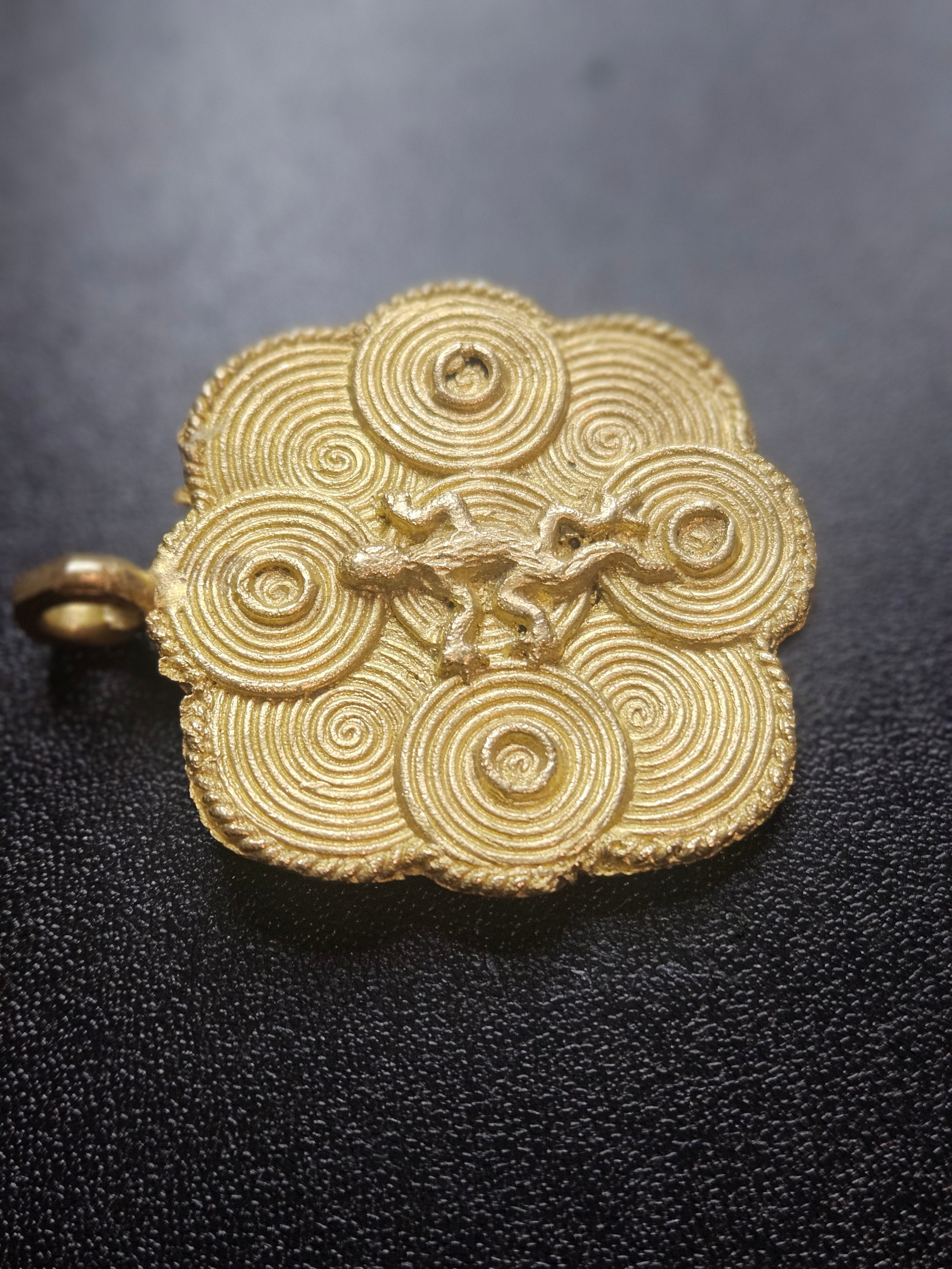 ashanti brass adinkra pendant dark background detail