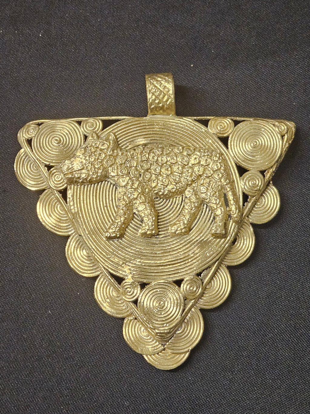 Triangular brass pendant with a raised leopard over a large spiral disc, smaller spiral details around the edges, and a top hanging loop
