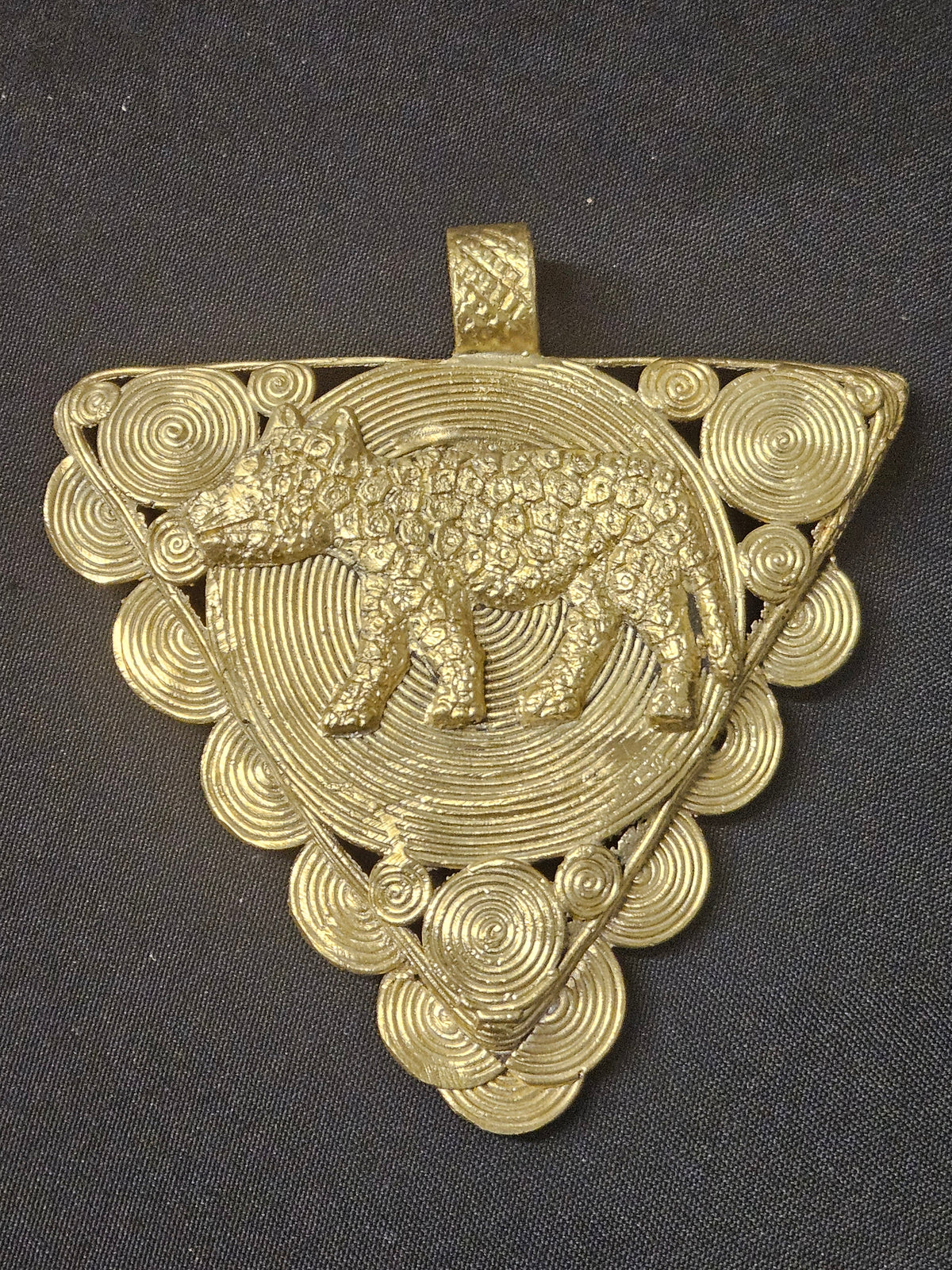 Triangular brass pendant with a raised leopard over a large spiral disc, smaller spiral details around the edges, and a top hanging loop