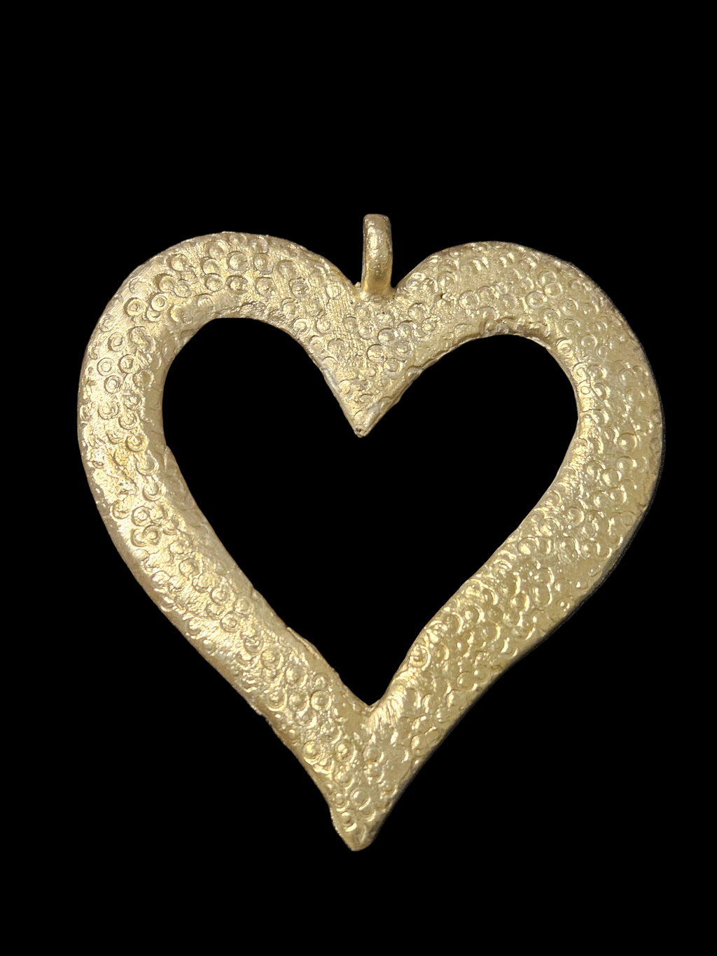 Brass Akoma pendant in an open heart shape with small circular surface patterns and a top hanging loop against a black background