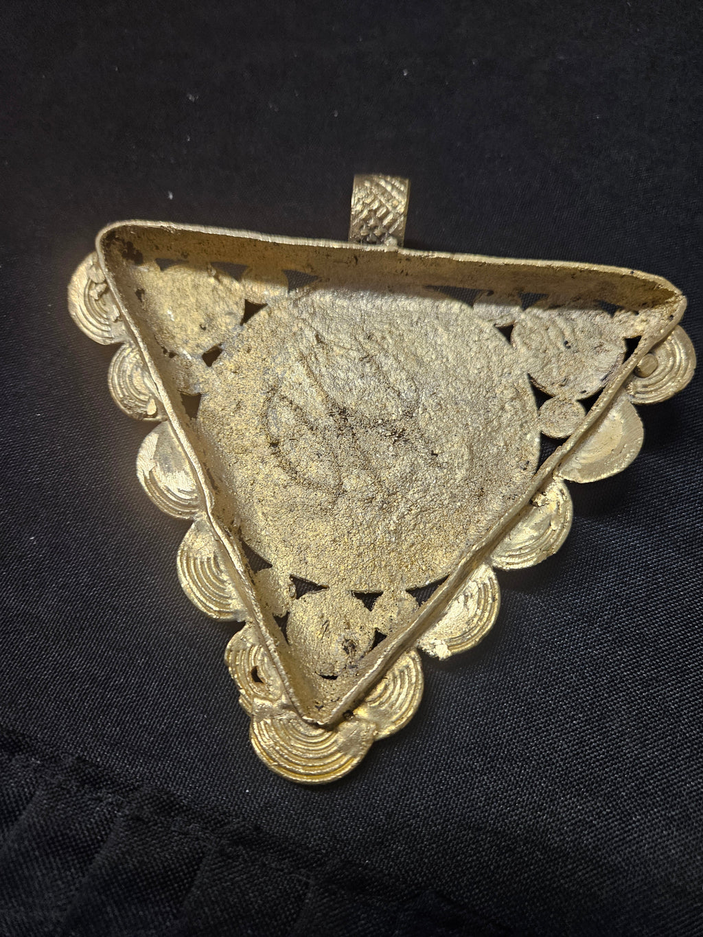 Rear view of the triangular brass Sankofa pendant showing its central back panel, spiral border, and top hanging loop