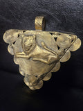Triangular brass pendant with a raised reclining lion over a large spiral disc, smaller spirals around the border, and a textured top hanging loop