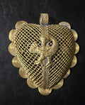 Brass pendant with a raised backward-looking Sankofa bird over a diamond lattice background, scalloped spiral borders, and a top hanging loop