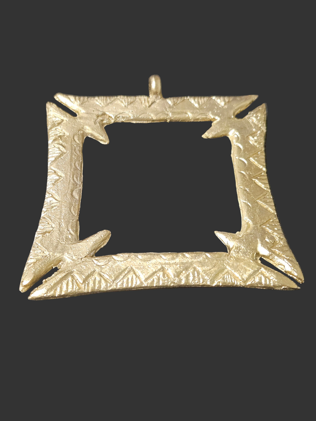 Brass Fihankra pendant with a square open center, pointed corner details, patterned borders, and a top hanging loop against a dark background