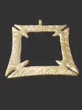 Brass Fihankra pendant with a square open center, pointed corner details, patterned borders, and a top hanging loop against a dark background