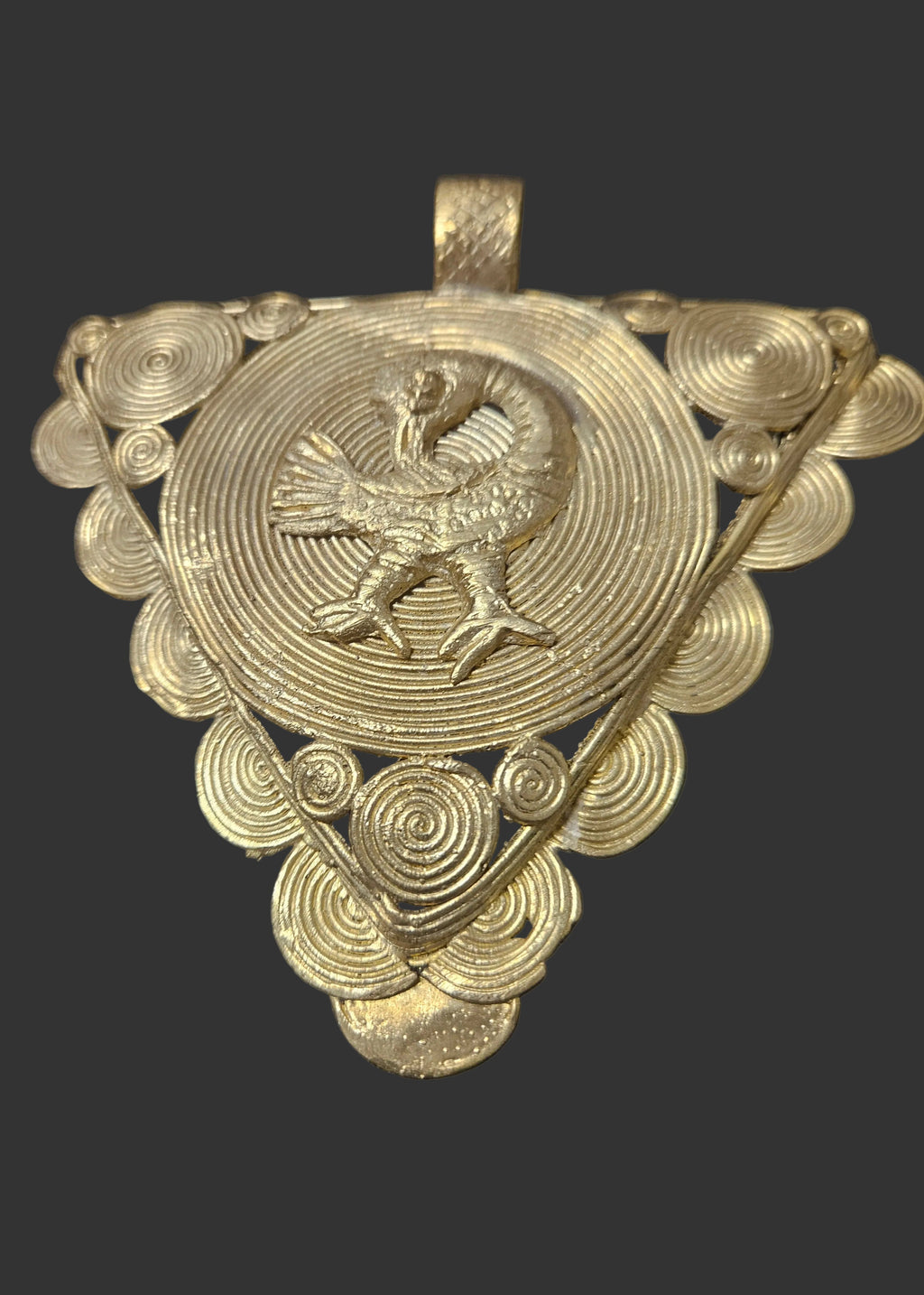 Triangular brass pendant with a raised backward-looking Sankofa bird over a large spiral disc, smaller spiral discs around the border, and a top hanging loop